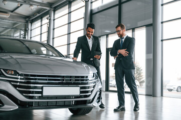 Talking about automobile. Man is consulting the customer in the car showroom