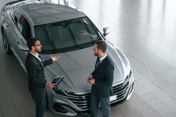Top view. Man is consulting the customer in the car showroom