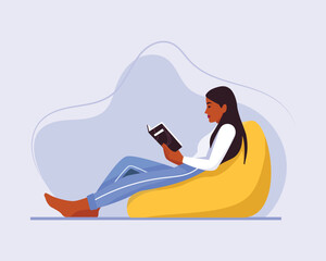 girl sitting on a chair (ottoman) with a book
