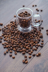 Coffee beans in glass cup on wooden table, top view