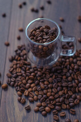 Coffee beans in glass cup on wooden table, top view