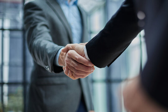 Two diverse professional business men executive leaders shaking hands at office meeting