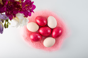 Obraz na płótnie Canvas easter pink eggs on a white background with a bouquet of spring freesias. Top view. 