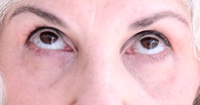 Brown eyes of elderly woman makes relaxing exercise for eyes. Hyperopia myopia astigmatism and glaucoma in retirement