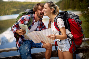 Man and girl  by the lake.Couple tourists with backpacks outdoors.