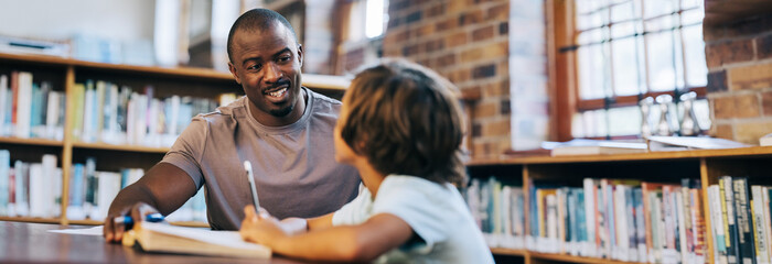 Male teacher counselling a young school boy in a library
