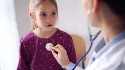Doctor and kid patient at home. Happy smiling child girl at usual medical inspection. Medicine, healthcare concepts