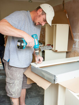 Kitchen Fitters: Making Drawers. A carpenter adding drawer fixtures to the carcass of a new kitchen build. From a series of related images.