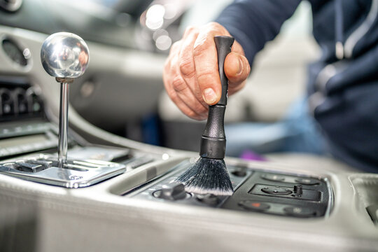 cleaning the interior of a luxury car with a brush
