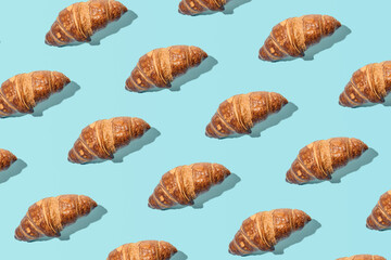 Fresh tasty croissants, creative food pattern against light blue background. 