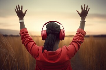 African-American woman with red headphones raising her arms in a wheat field, enjoying nature and music. Generative AI