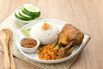 Bebek Goreng Kremes, served with chili sauce (sambal) and cucumber. Indonesian food
