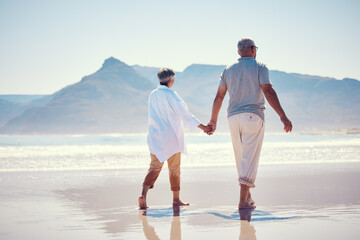 Holding hands, love and an old couple walking on the beach in summer with blue sky mockup from behind. Care, romance or mock up with a senior man and woman taking a walk on the sand by the ocean