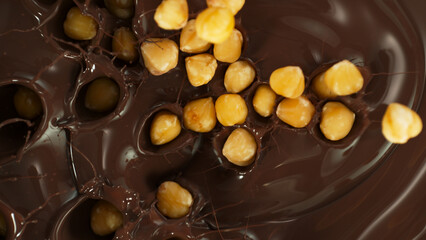 Close-up of Falling Whole Hazelnuts into Melted Chocolate
