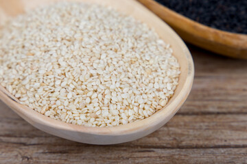 White sesame in a wooden spoon close-up.