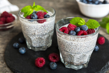 Healthy breakfast or morning with chia seeds vanilla pudding raspberry and blueberry berries on table background, vegetarian food, diet and health concept. Chia pudding with raspberry and blueberry