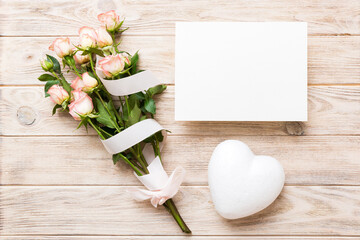 Greeting holiday card mockup with fresh roses on colored table background, mock up with copy space for design