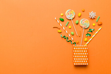 gift box in corner full of assorted traditional candies falling out on colored background with copy space. Happy Holidays sale concept