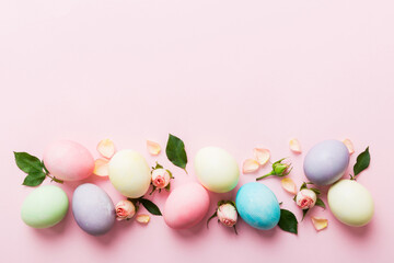 Happy Easter. Easter eggs on colored table with yellow roses. Natural dyed colorful eggs background top view with copy space