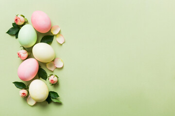Happy Easter. Easter eggs on colored table with yellow roses. Natural dyed colorful eggs background top view with copy space