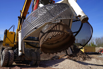 Excavator with manhole cover tiller on a housing construction site