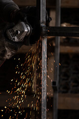 Closeup photo of metalworking in dark workshop. Welding and grinding with lot of sparks and smoke