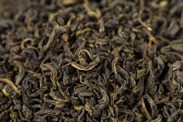 dry tea leaves in wooden spoon background.