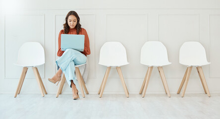 Waiting room, sitting and a woman with a laptop for email, preparation and interview research....