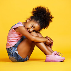 Portrait, shy and girl child on studio floor for children fashion, playful and sweet against yellow...