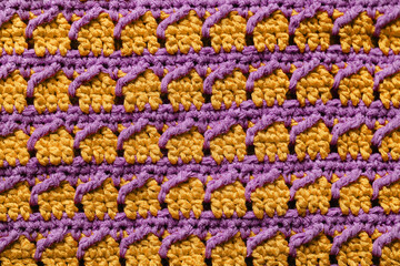 Fototapeta na wymiar Yellow violet seamless knitted texture. Cross over stitch pattern. Volumetric crochet striped pattern. Knitted background.
