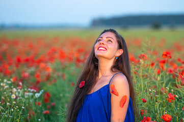Naklejka na ściany i meble pretty young woman with long hair playing with petals in poppy field in evening sunlight