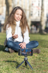 Young happy preteen girl recording a vlog outside in a sunny day, being online