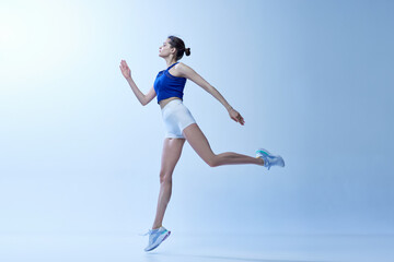 Fototapeta na wymiar Active sportive young girl in comfortable sportswear training, doing workout exercises against light blue studio background. Concept of sport, healthy and active lifestyle, beauty, fitness