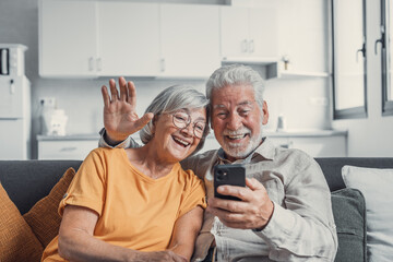 Happy retired family couple using mobile phone for video call together, talking to relations,...