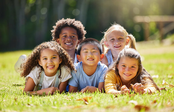 Portrait, smile and children lying on grass in nature on vacation outdoor for learning. Kids, diversity and happiness of group enjoying summer holiday at park or garden, bonding or relaxing together.