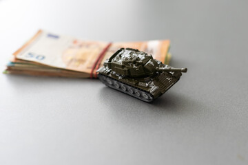 Economic crisis concept. Toy military tank on euro banknotes. War conflict in Ukraine, economic sanctions and inflation
