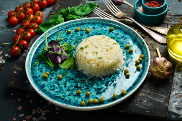 Boiled rice with vegetables on a plate. On a dark background.
