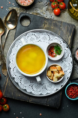 Chicken soup in a white bowl. Close-up, dark background.