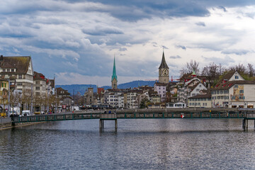 Fototapeta na wymiar Scenic view of the old town of City of Zürich with Limmat River, quayside and footbridge on a cloudy spring day. Photo taken March 31st, 2023, Zurich, Switzerland.