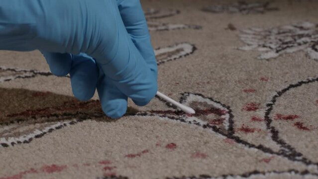 Slide shot of forensic office gather blood samples off the carpet