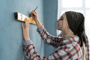 Side view of couple doing house renovation together. Woman and her boyfriend using measurement level redecorating apartment