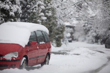 Fototapeta na wymiar Red car parked on a very snowy estate road