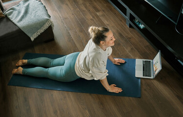 Woman doing online yoga at home. Female trener teaches asana in