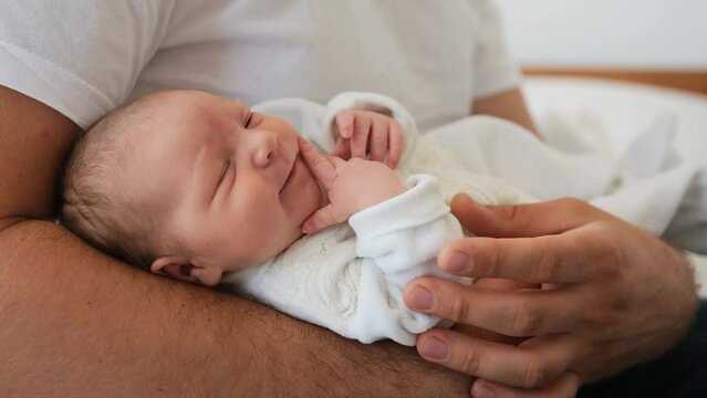 Adorable newborn baby yawning lying on his father legs and falling asleep. Closeup view of sweet infant child and parent dad. Moments of fatherhood