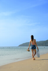 Fototapeta na wymiar Asian woman walking along the beach
