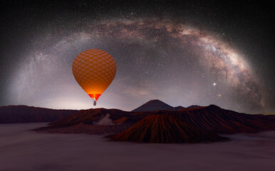Hot air balloon is flying over the Bromo mountain,  Amazing Milky way galaxy in the background -...