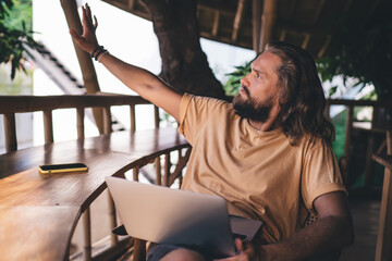 Bearded man sitting with laptop in balcony