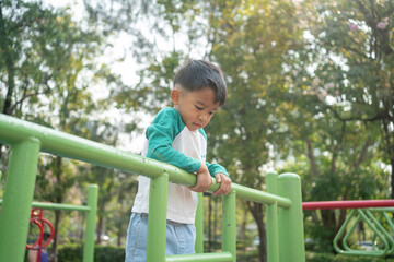 Happy asian boy climbing in outdoor playground public park
