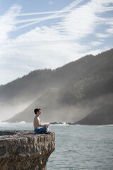 Teenager boy meditating in beautiful landscape