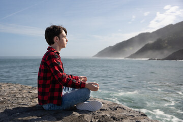 Teenager boy meditating at coast